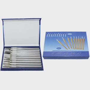 May include: A set of silver and gold carving knives in a blue box. The box is open, revealing a row of knives with silver handles and various blade shapes. A second box with a blue lid displays additional knives.