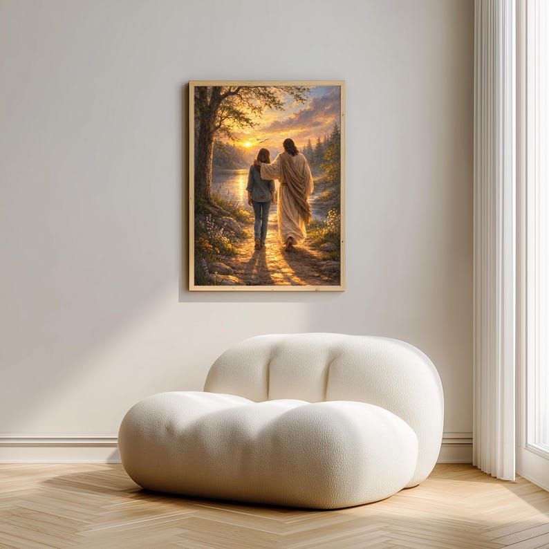 May include: A framed artwork depicts two figures walking on a path towards a sunset. The figures are illuminated by the golden light, with a lake and trees in the background. The artwork is displayed on a white wall above a white, rounded chair.