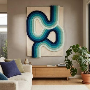 May include: A rectangular wall hanging featuring a textured cream-colored base with a raised, tufted design of interconnected, winding lines in gradient shades of teal, turquoise, and dark navy blue that extend beyond the top edge of the base.