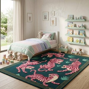 May include: A child's bedroom with a teal rug featuring pink tiger designs. The room includes a white bed with pastel bedding, a bookshelf with books, and framed bear art. Soft toys and wooden blocks add to the playful decor.