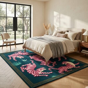May include: A teal rug with a pink tiger design in a bedroom setting. The rug features multiple tigers in various poses, with green foliage accents and a gold border. The bedroom includes a bed, chair, and a window.