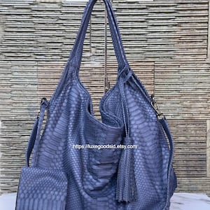 May include: A blue hobo bag with a textured snakeskin pattern, featuring two top handles, a detachable shoulder strap, and a matching rectangular wallet. A decorative tassel hangs from the side, and the text https://luxegoodsid.etsy.com is visible.