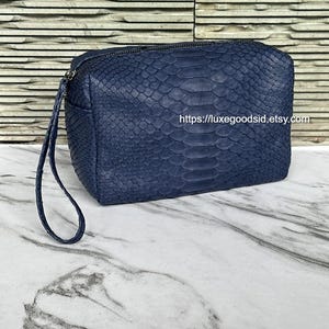May include: A navy blue, rectangular cosmetic bag with a textured snakeskin pattern. The bag has a zipper closure and a small wrist strap. The Etsy shop URL is visible on the image.