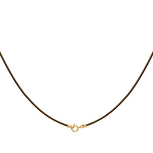 May include: A brown necklace with a gold-colored clasp. The necklace is a simple design, with a thin, dark brown cord. The clasp is round and appears to be made of gold-colored metal.