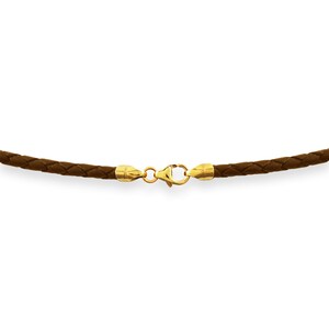 Peut inclure: Un collier en cuir tressé marron avec des fermoirs et des embouts dorés. Le collier est centré sur un fond blanc, mettant en valeur la texture et la couleur du cuir et l'éclat du métal.