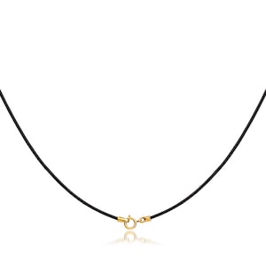 May include: A black necklace cord with a gold-coloured clasp. The cord is smooth and appears to be made of a flexible material. The clasp is round and has a simple design. The necklace is displayed against a white background.