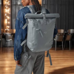 May include: A gray roll-top backpack with a zippered pocket and the initials "RD" on the front.