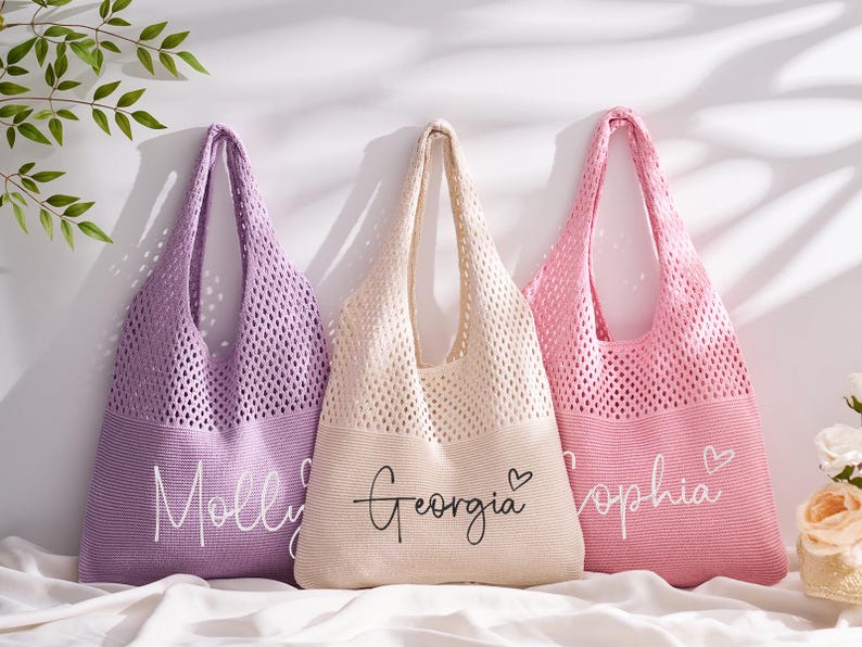 May include: Three personalised tote bags in lavender, cream, and pink. Each bag features a knitted mesh upper and a solid bottom with a name in script. The lavender bag says "Molly", the cream bag says "Georgia", and the pink bag says "Sophia".