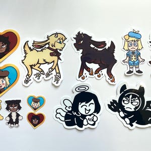 May include: A collection of colorful stickers featuring cartoon characters. The stickers include images of goats, angels, devils, and characters in heart-shaped frames. The characters are in various outfits and poses, with a mix of cute and edgy designs.