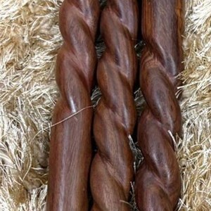 May include: Three wooden furniture legs with a twisted design, showcasing a rich brown color. The legs have metal threaded ends for attachment and are set against a textured, light brown background.