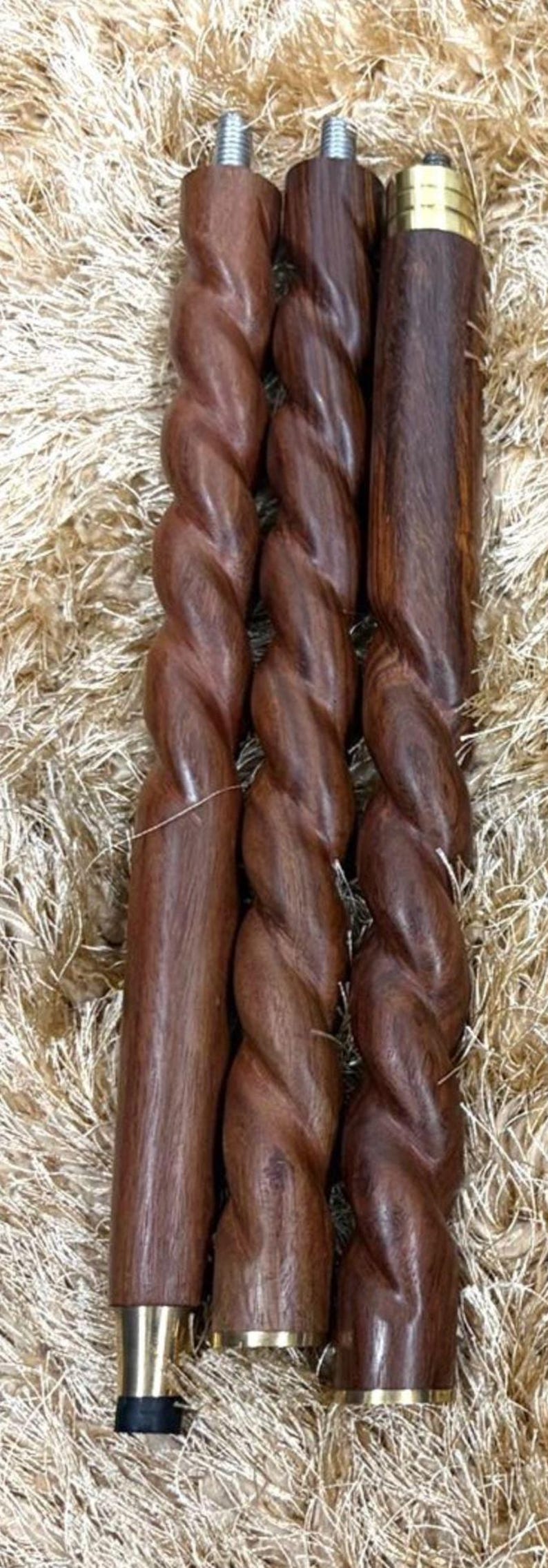May include: Three wooden furniture legs with a twisted design, showcasing a rich brown color. The legs have metal threaded ends for attachment and are set against a textured, light brown background.