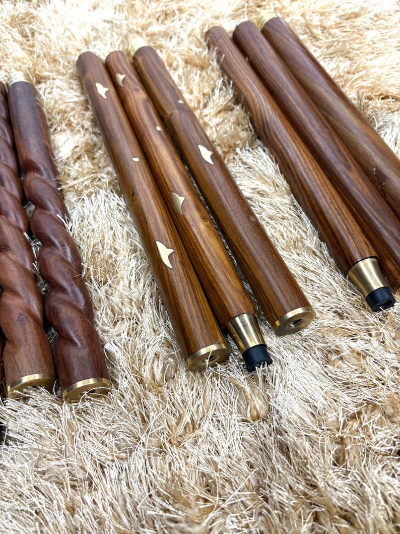 May include: A collection of wooden furniture legs with brass accents. Some legs are smooth, while others have a twisted design. Several legs have a star-shaped inlay. The legs are a rich brown color.