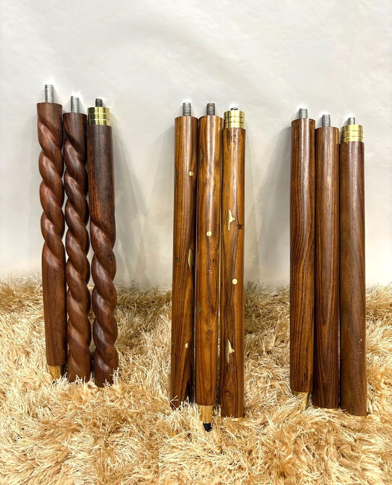 May include: A collection of wooden furniture legs in various designs. Some legs have a twisted rope design, while others are straight with decorative inlays. All legs have metal threaded tops and brass-colored accents.