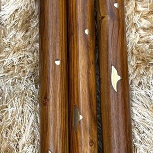 May include: Three wooden furniture legs with a rich brown finish and decorative brass accents. The legs are cylindrical, with a threaded top and a brass-colored base. Each leg has a unique wood grain pattern.