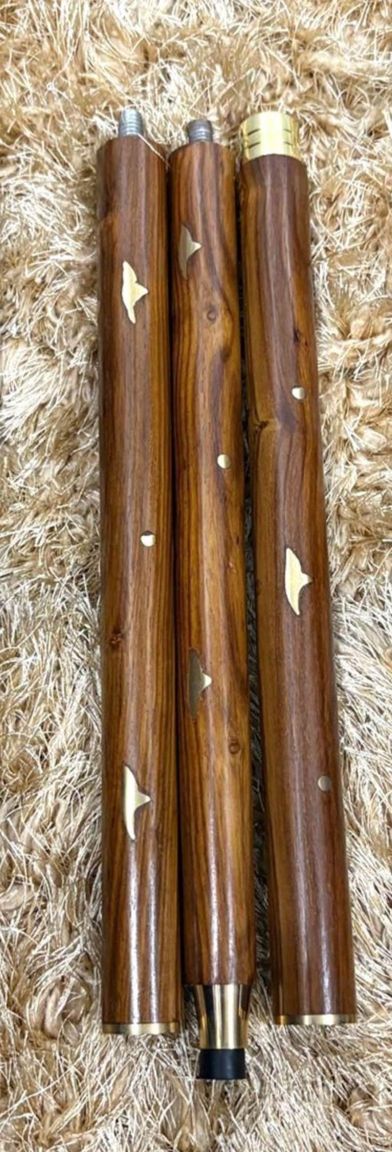 May include: Three wooden furniture legs with a rich brown finish and decorative brass accents. The legs are cylindrical, with a threaded top and a brass-colored base. Each leg has a unique wood grain pattern.