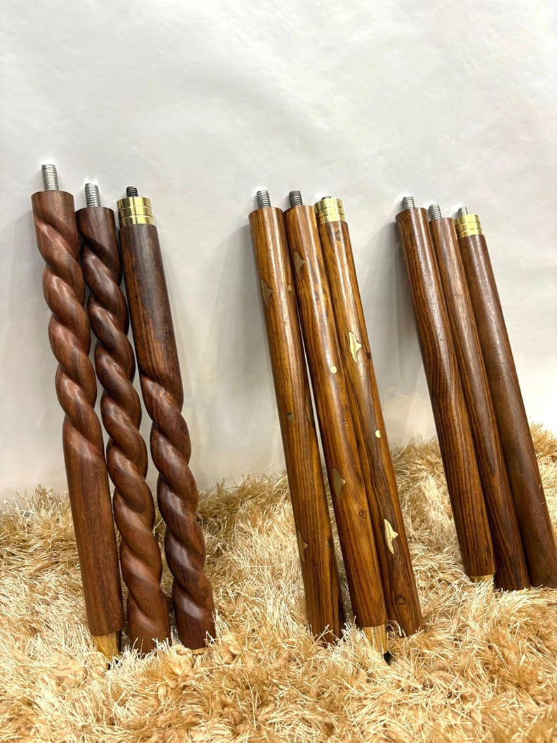 May include: A collection of wooden furniture legs in various designs. Some legs feature a twisted rope design, while others are straight with brass accents and decorative inlays. The legs are a rich brown color, suggesting a natural wood finish.