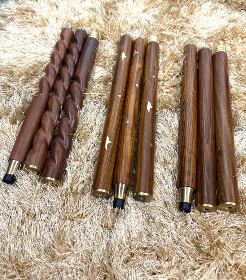 May include: A collection of wooden furniture legs in various designs. Some legs have a twisted rope design, while others are straight with brass accents and star-shaped inlays. The legs are a rich brown color and have black rubber feet.