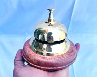 Timbre de recepción de hotel de latón náutico con base de madera.