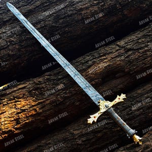 May include: A long, ornate sword with a patterned blade and gold-colored hilt. The hilt features red accents and a detailed design. The sword is displayed against a dark, textured wooden background.