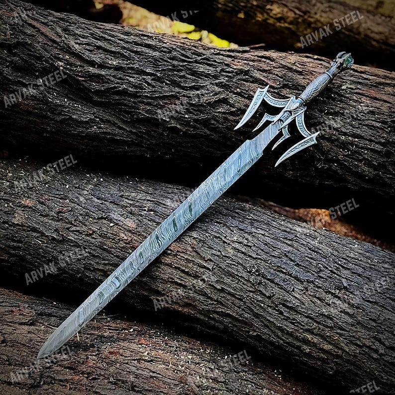 May include: A decorative sword with a patterned blade and ornate hilt. The hilt features a detailed design with a green accent. The blade has a unique, textured pattern. The sword is displayed on a bed of wooden logs.