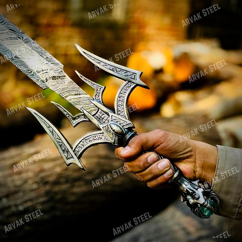May include: A detailed view of a decorative sword with a silver-colored handle and blade. The blade has a unique pattern, and the handle features intricate designs. The sword is held in a hand, showcasing its craftsmanship.