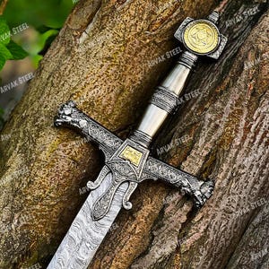 May include: A detailed sword with a silver blade and handle, featuring intricate engravings and gold accents. The hilt has a star emblem. The text "ARVAK STEEL" is visible on the sword.