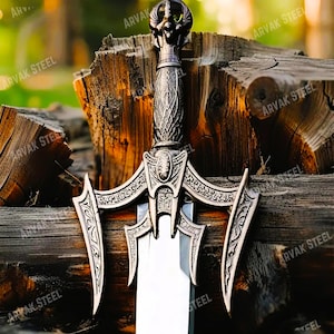 May include: A detailed close-up of a decorative sword with an ornate handle and blade. The sword features intricate carvings and a silver finish. The blade is sharp and polished, reflecting the light. The sword is set against a wooden background.