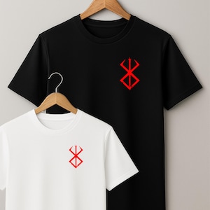 May include: Two t-shirts, one black and one white, each featuring a red graphic on the chest. The graphic is a stylized symbol. The shirts are suspended on a wooden hanger against a plain backdrop.