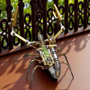 May include: A detailed steampunk insect sculpture made from metal components. The sculpture combines brass, silver, and glass elements, with articulated legs and pincers. It rests on a brown surface, with a blurred green backdrop.