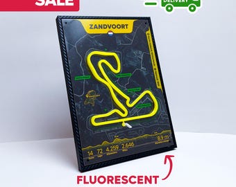 Könnte beinhalten: Eine schwarz gerahmte 3D-Streckenkarte von Zandvoort, Niederlande, mit einer leuchtend gelben fluoreszierenden Streckenkontur. Die Karte enthält den Text "Zandvoort", "14 Kurven", "4.259 Kilometer" und "8.9 m Höhenunterschied". Die Wörter "SALE" und "KOSTENLOSE LIEFERUNG" sind ebenfalls sichtbar.