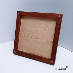 This image shows the back of a framed 3D printed miniature map of Central Park in Manhattan, New York City. The wooden frame has a warm finish, with a wire hanging mechanism attached for wall display. The backing is plain, highlighting the frame's craftsmanship. The photo emphasizes the high-quality materials and construction, making it clear that this modern wood-framed wall art is an elegant and stylish piece, perfect for gifting or decorating a Manhattan-themed space.