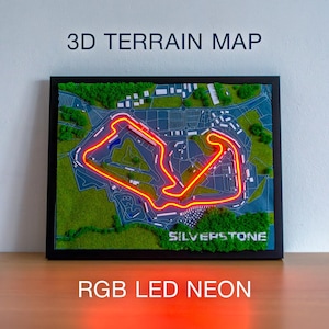 以下が含まれることがあります： シルバーストーンレーストラックの3D地形図。ネオンで照らされたトラックの輪郭が特徴です。緑、青、白の要素が含まれ、「3D TERRAIN MAP」と「SILVERSTONE」の文字が表示されています。下部のテキストは「RGB LED NEON」です。