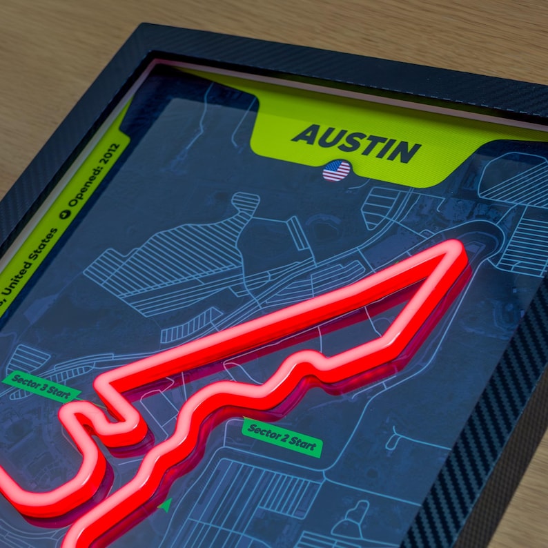 Illuminated wall art poster of the Austin Formula 1 Circuit of the Americas track, featuring a glowing red neon-style track layout over a dark map background. The design includes labeled sector start points, a bright yellow “Austin” header with a small U.S. flag, and a sleek black frame, styled as modern LED decor celebrating the United States Grand Prix and Charles Leclerc’s fastest lap.