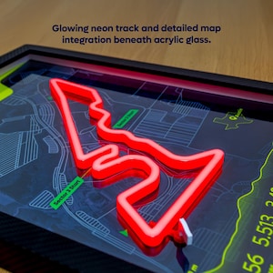 Close-up detail of the Austin Neon F1 Track Poster featuring the United States Grand Prix circuit in Austin, Texas. A raised red LED-style track outline representing Charles Leclerc’s Ferrari fastest lap glows beneath clear acrylic glass, layered over a detailed map background with sector markers and circuit information. The framed motorsport wall art highlights the 3D neon effect and premium construction.