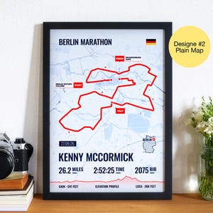 May include: Framed print of the Berlin Marathon map, with a red route marking the course. Text includes "Berlin Marathon", date, runner's name, time, distance (26.2 miles), and elevation profile. A German flag is in the top right corner.