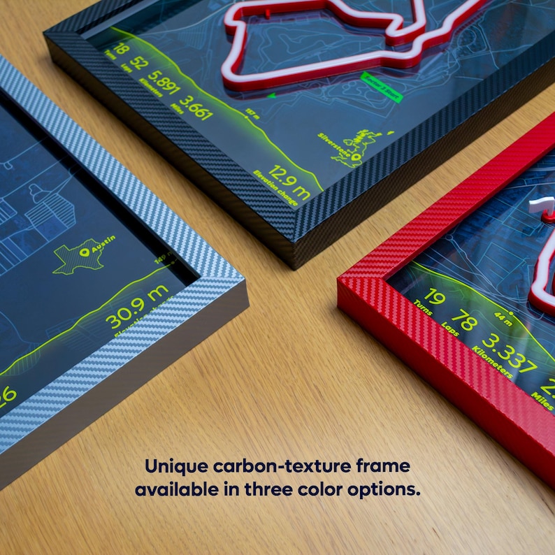 Three framed circuit track maps with carbon-texture frames in black, red, and grey. Each frame displays a track layout with highlighted features and measurements. The text in the image says "Unique carbon-texture frame available in three colour options."