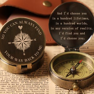 May include: A vintage-style compass in a bronze finish. One side reads "SO YOU CAN ALWAYS FIND YOUR WAY BACK TO ME" around a compass rose. The other side of the compass reads "And I'd choose you in a hundred lifetimes..."