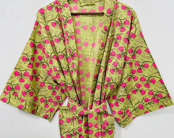 May include: A light green robe with a floral pattern of pink flowers and brown stems. The robe has wide sleeves and a matching belt. The robe is hanging on a wooden hanger against a white background.