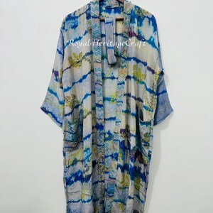 May include: A long, flowing kimono-style robe in shades of blue, white, and yellow, with a tie-dye pattern. The robe has wide sleeves and pockets. The text "Royal Heritage Craft" is visible on the front.
