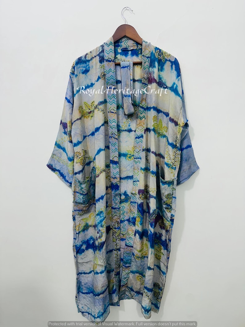 May include: A long, flowing kimono-style robe in shades of blue, white, and yellow, with a tie-dye pattern. The robe has wide sleeves and pockets. The text "Royal Heritage Craft" is visible on the front.