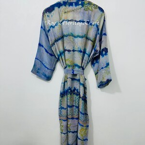 May include: A blue and white patterned robe with a tie belt, hanging on a wooden hanger. The robe has a tie-dye effect with blue and green accents. The text "Royal Heritage Craft" is visible on the robe.