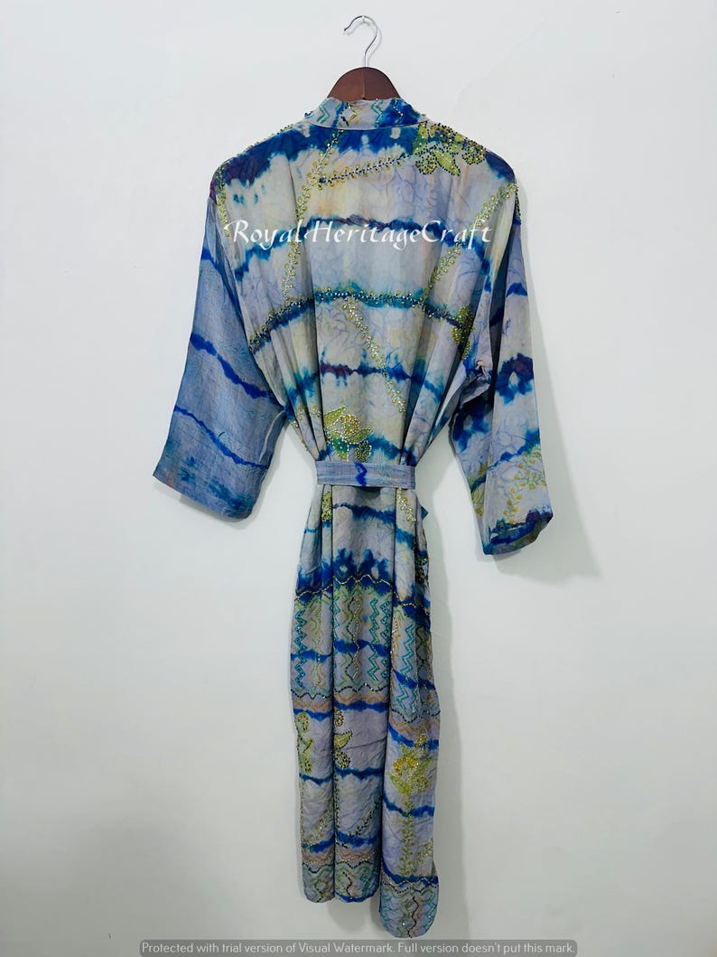 May include: A blue and white patterned robe with a tie belt, hanging on a wooden hanger. The robe has a tie-dye effect with blue and green accents. The text "Royal Heritage Craft" is visible on the robe.