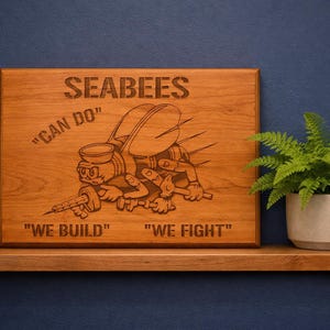 May include: A wooden plaque with the word "SEABEES" engraved at the top. The plaque features a cartoon character holding tools and a syringe. The phrases "CAN DO", "WE BUILD", and "WE FIGHT" are also engraved.