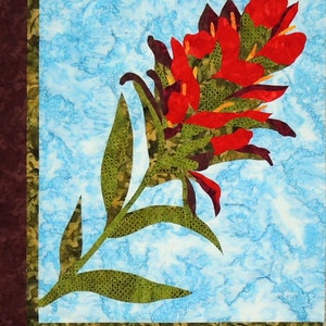 May include: A red and green applique of a flower with a single stem and leaves against a blue and white background.