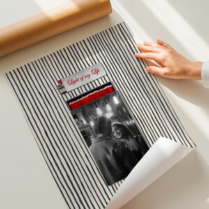 May include: A black and white striped poster with a photograph of a couple. The poster has the text "Light of my Life" on the top. A brown cardboard tube is in the background.