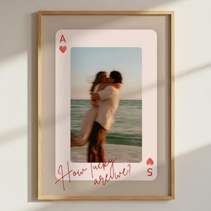 May include: Framed art print with a photograph of a couple embracing on a beach, presented as the Ace of Hearts playing card. The text "How lucky are we?" is written in red script across the card.