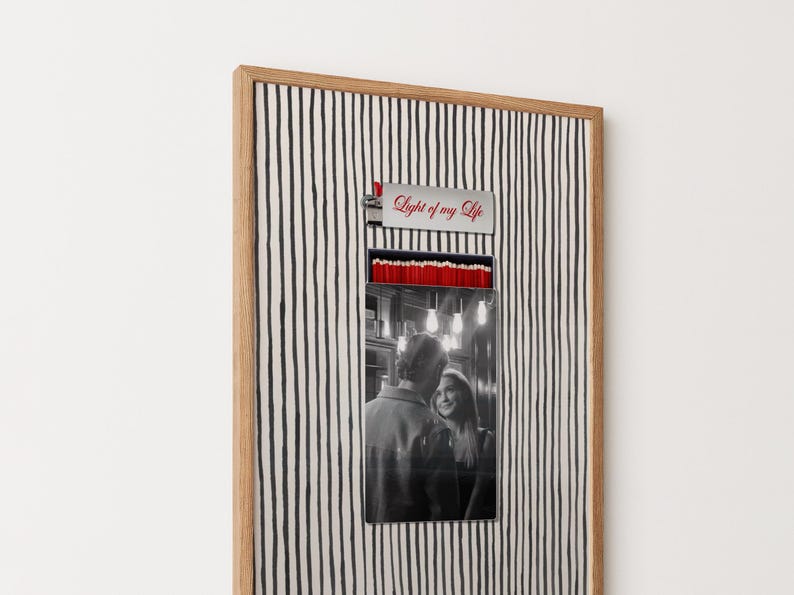 May include: A framed artwork featuring a black and white photo of a couple. The frame has a striped background and a wooden border. Above the photo is a metal piece with the text "Light of my Life" in red.
