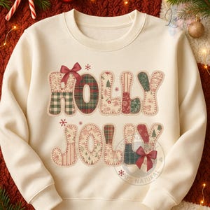 Puede incluir: Sudadera de color crema con las palabras "HOLLY JOLLY" en un diseño de patchwork. Las letras están hechas de varias telas estampadas, incluyendo cuadros y estampados florales, y están adornadas con lazos rojos y pequeñas estrellas. Un tema festivo de vacaciones.