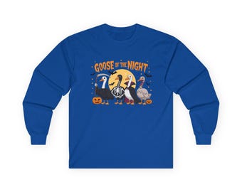 May include: A blue long-sleeved shirt with a Halloween design. The graphic shows four geese in costumes, with the words "Goose of the Night". The geese are in a graveyard scene with pumpkins and bats, perfect for the spooky season.