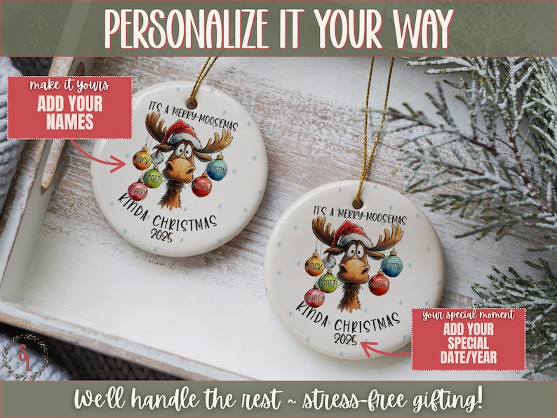 May include: Two round Christmas ornaments with a moose design. The ornaments have the text "It's a Merry-Moosemas Kinda Christmas 2025". Each ornament has a gold string for hanging. The ornaments are on a white tray.